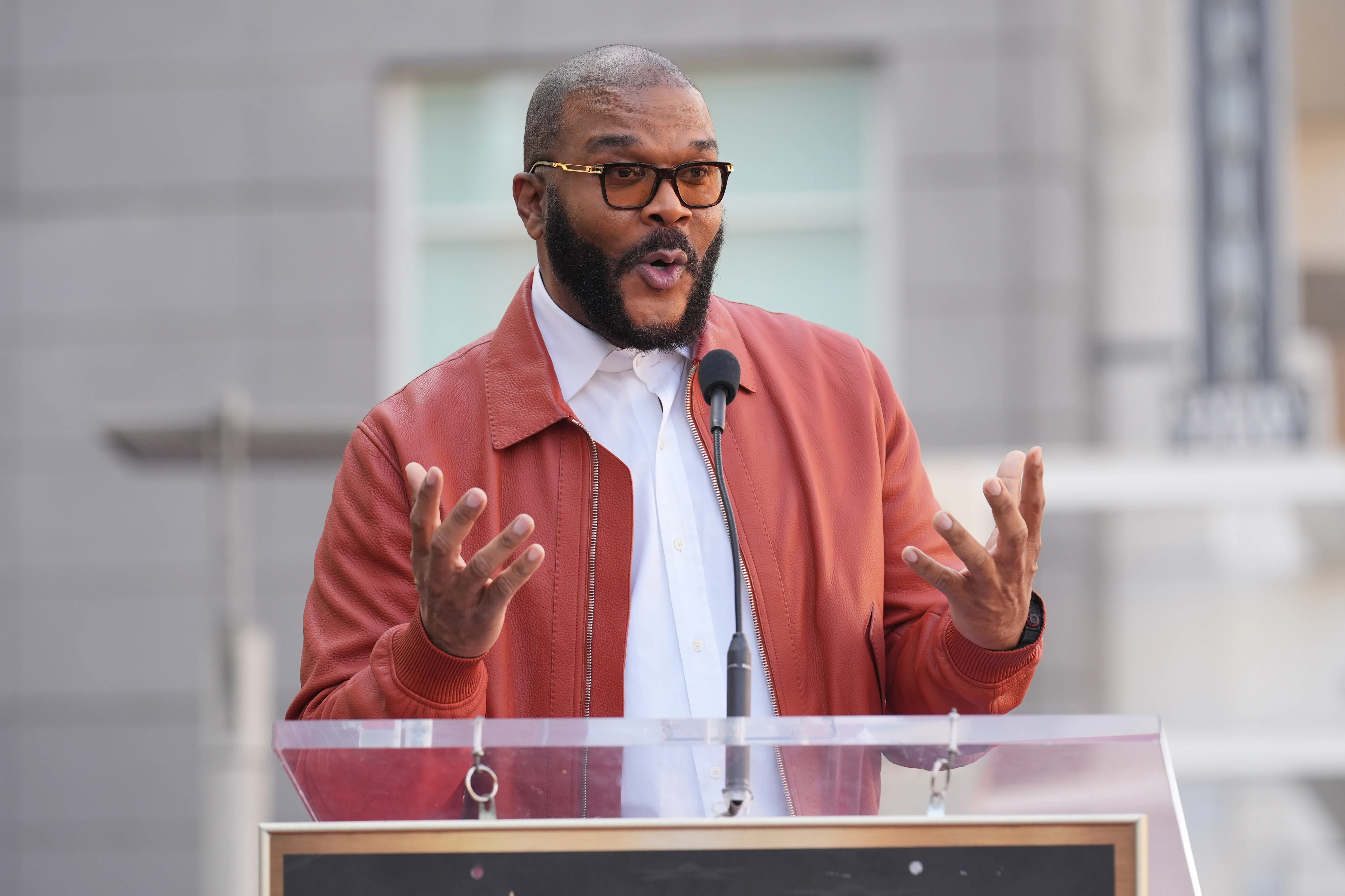 Tyler Perry speaking at a podium.