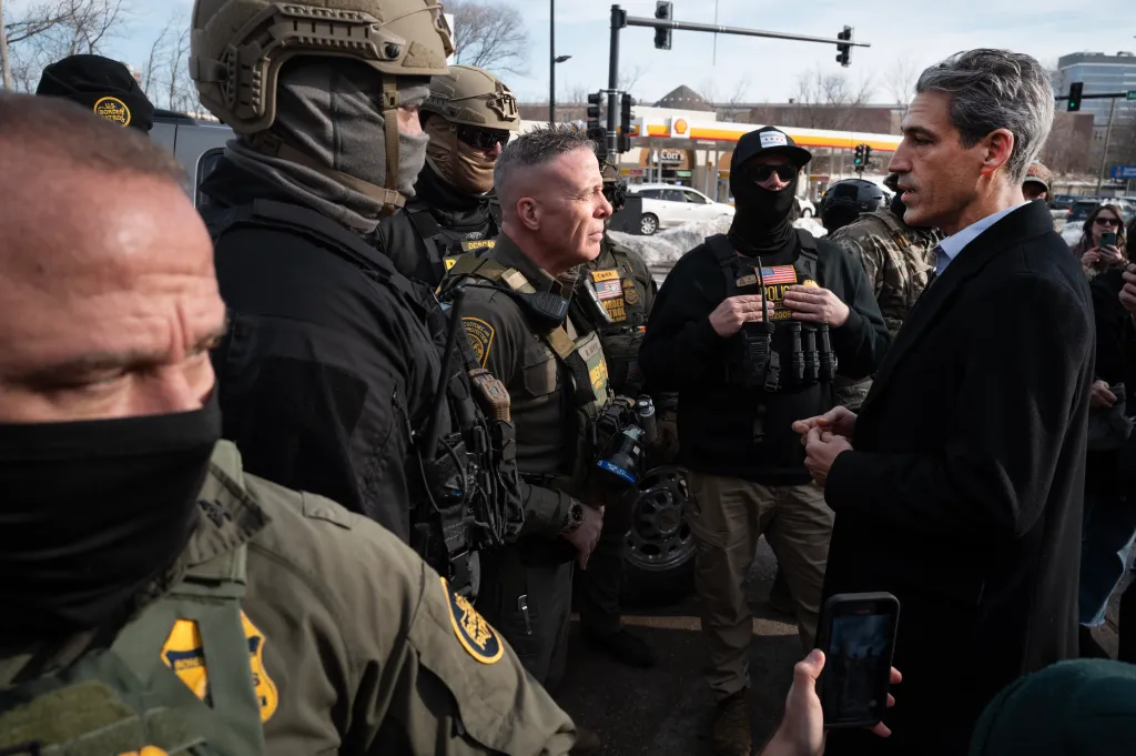 U.S. Border Patrol Chief Gregory Bovino speaks with Evanston Mayor Daniel Biss while surrounded by other agents.