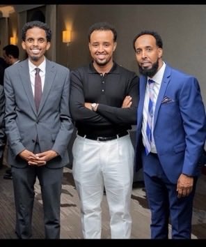 Three Somali men, one a fraudster, posing together.
