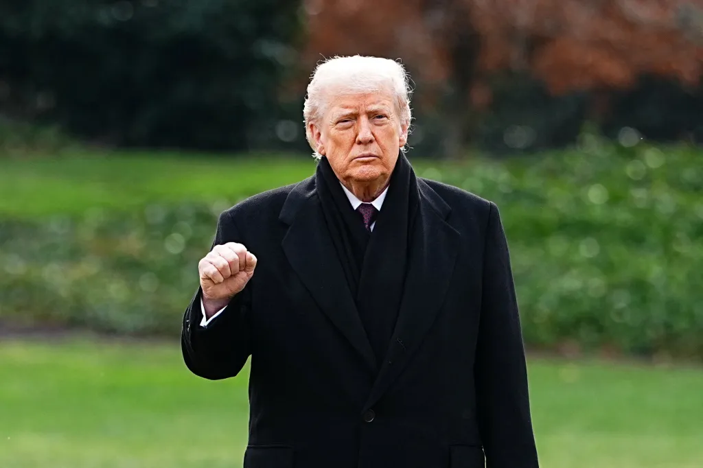 U.S. President Donald Trump wearing a black coat and scarf, clenches his fist in front of him.