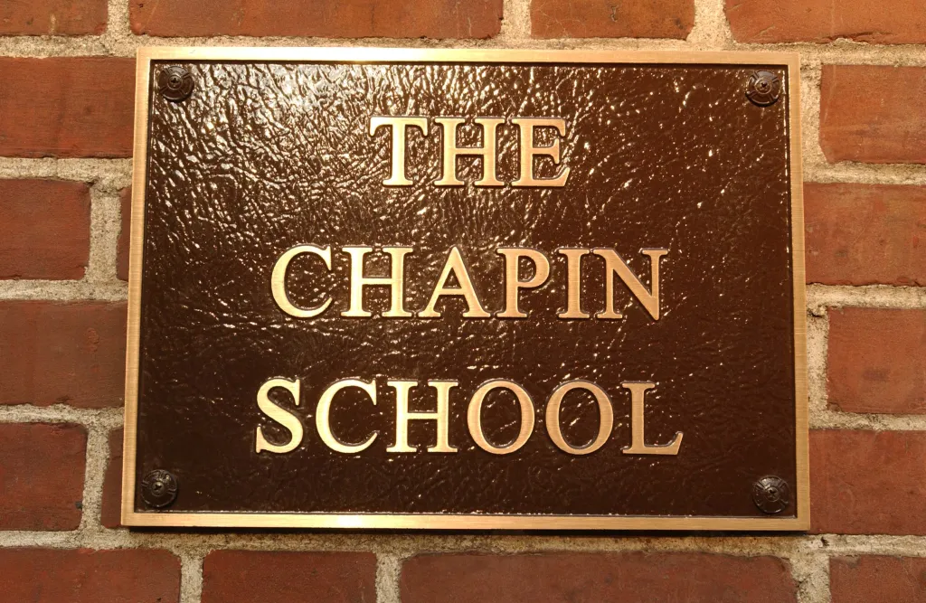 Bronze plaque on a brick wall reads