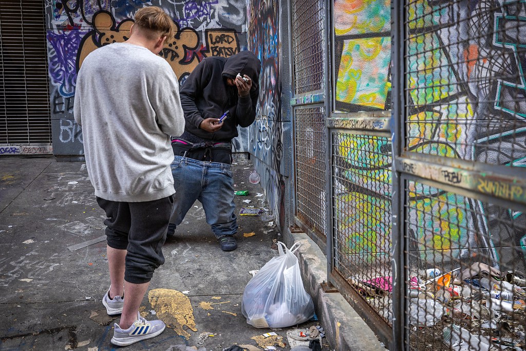 Two drug users holding pipes in 
