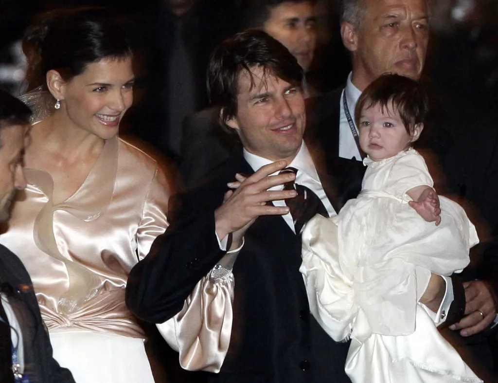 Tom Cruise holds his baby daughter Suri as Katie Holmes smiles beside them.