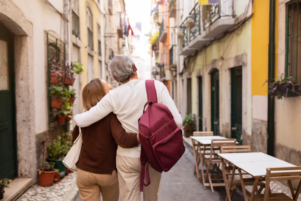 Back view of a senior couple, hugging, walking down a street in Lisbon.