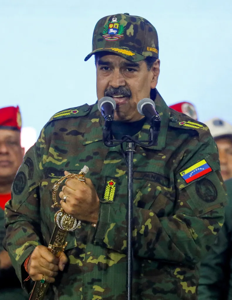 Venezuelan President Nicolas Maduro in military camouflage holding Simon Bolivar's sword and speaking at a rally.