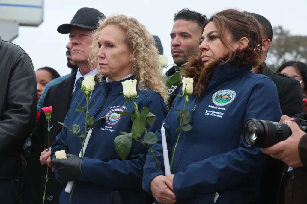 People holding roses and candles at a vigil for victims of a mass shooting.