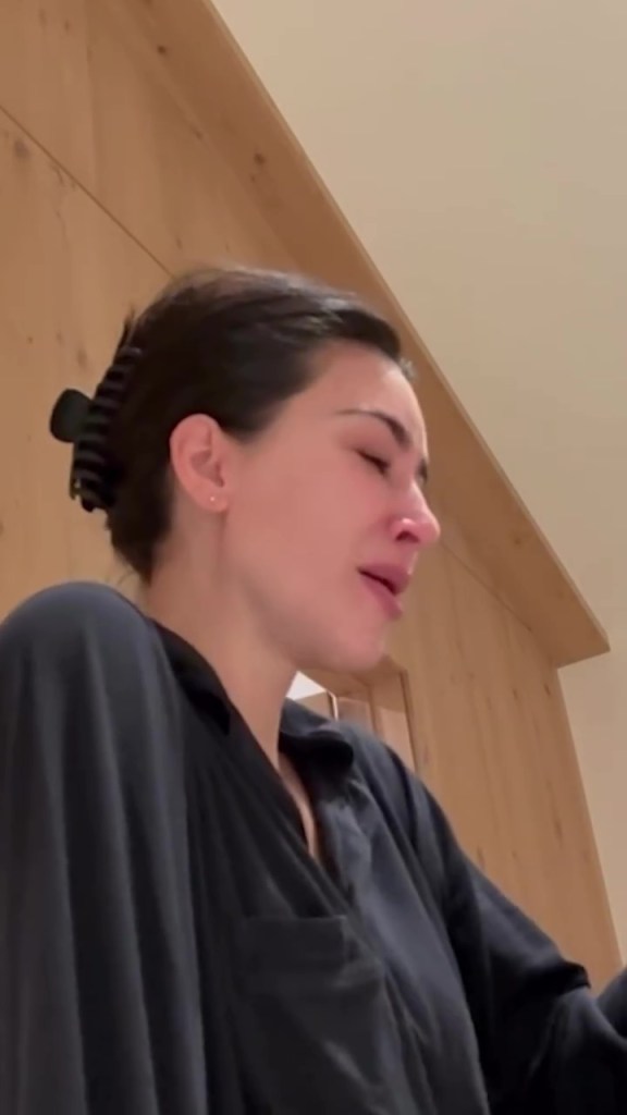 Kim Kardashian crying, wearing a black shirt and with her hair pulled back.