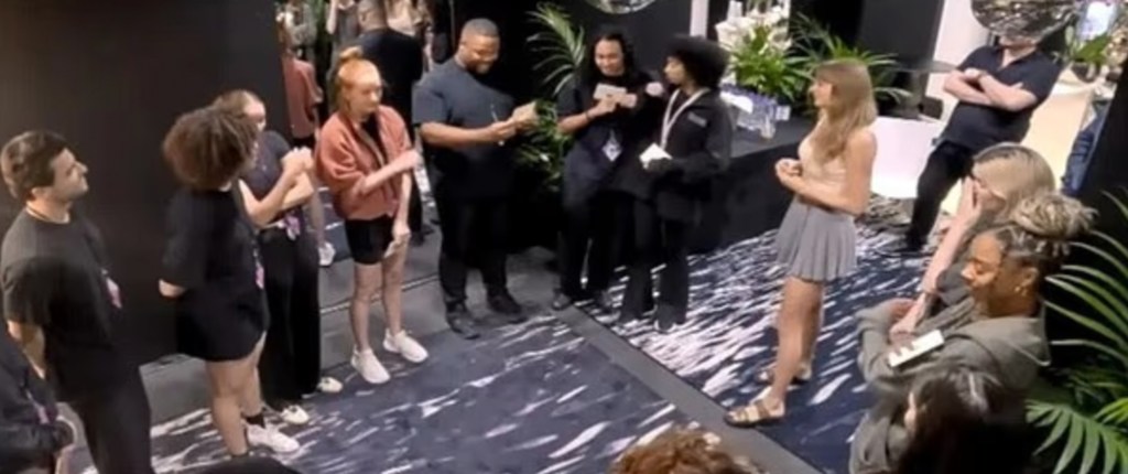 Taylor Swift greeting her Eras Tour crew while standing in a room.
