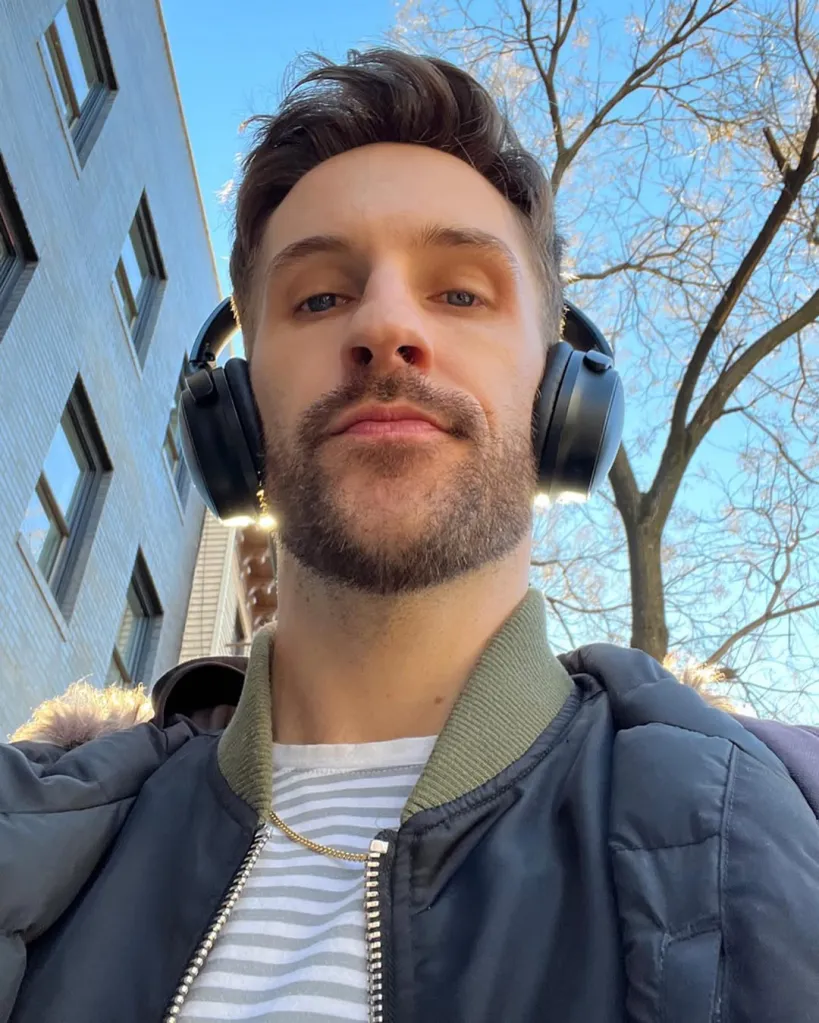 Jimmy Fowlie wearing headphones, a striped shirt, and a dark bomber jacket.