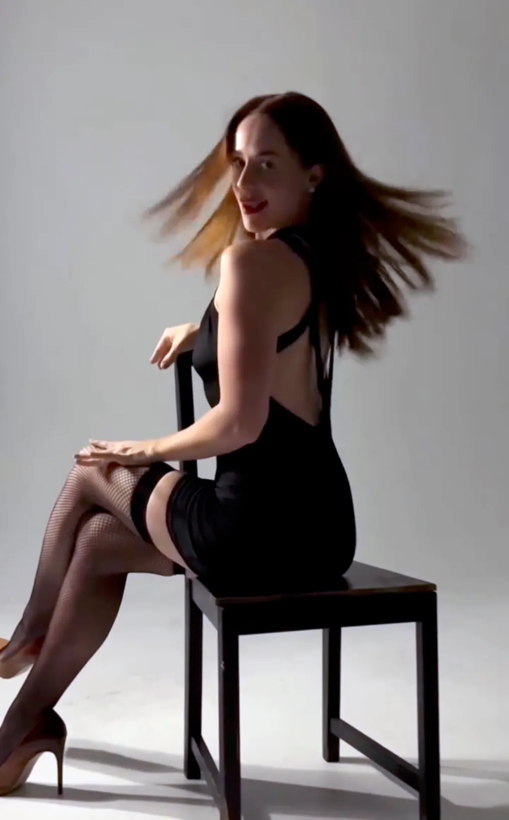 Whitney Leavitt as Roxie Hart in a black dress, thigh-high stockings, and tan heels.