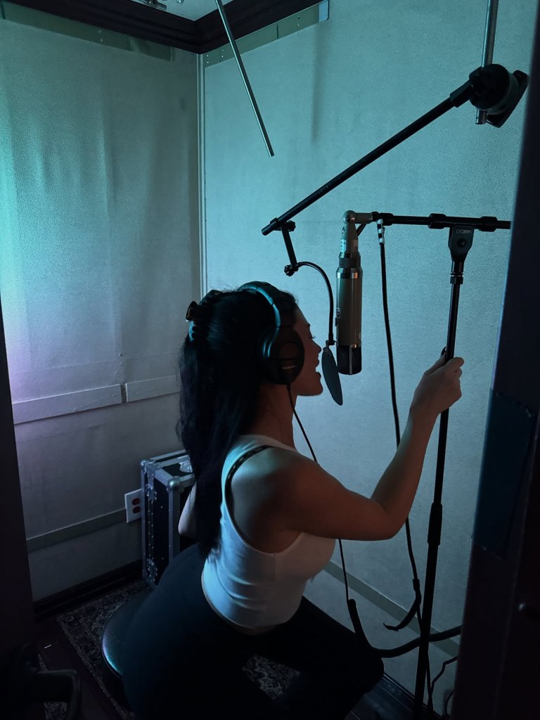 Kylie Jenner singing into a studio microphone.