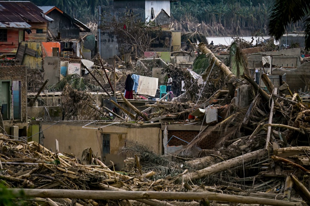 A woman hangs laundry amidst a devastating flood in Aceh Tamiang, Aceh province.