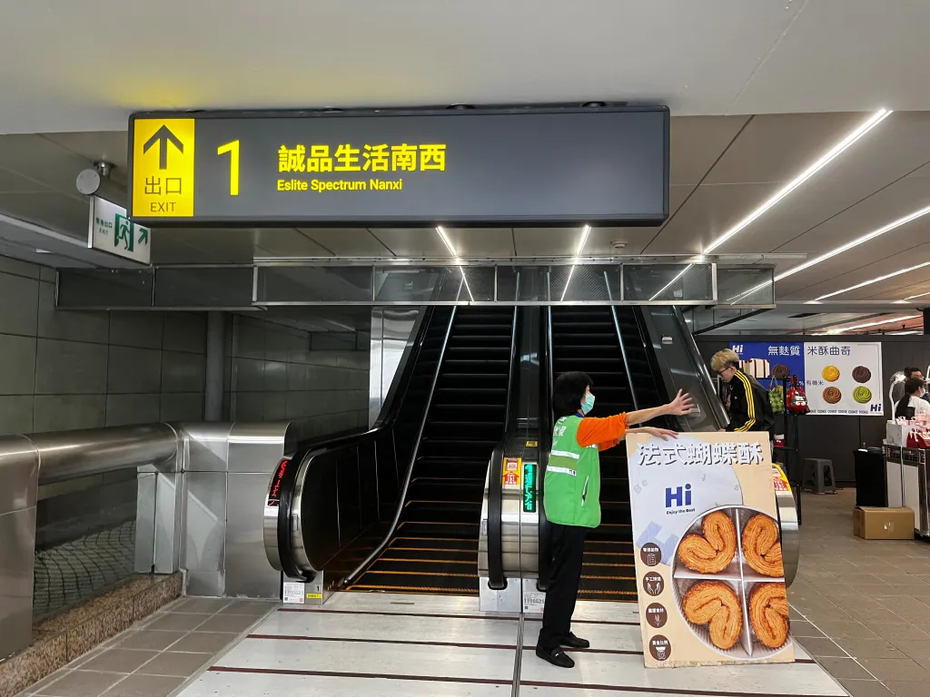 A worker gestures in front of escalators at an exit towards Eslite Spectrum Nanxi at Zhongshan station in Taipei, Taiwan.