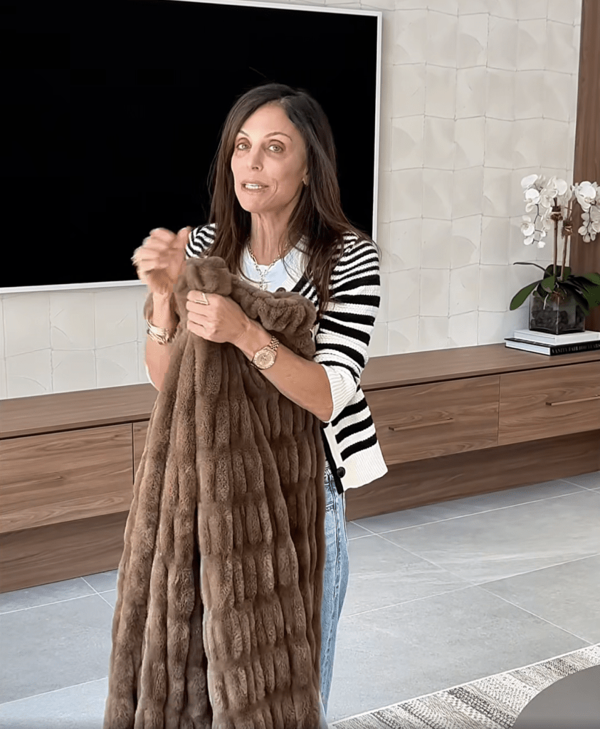 Bethenny Frankel holding up a brown faux fur blanket.