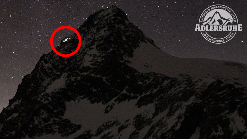 Webcam image of Großglockner mountain at night with two emergency lights glowing.