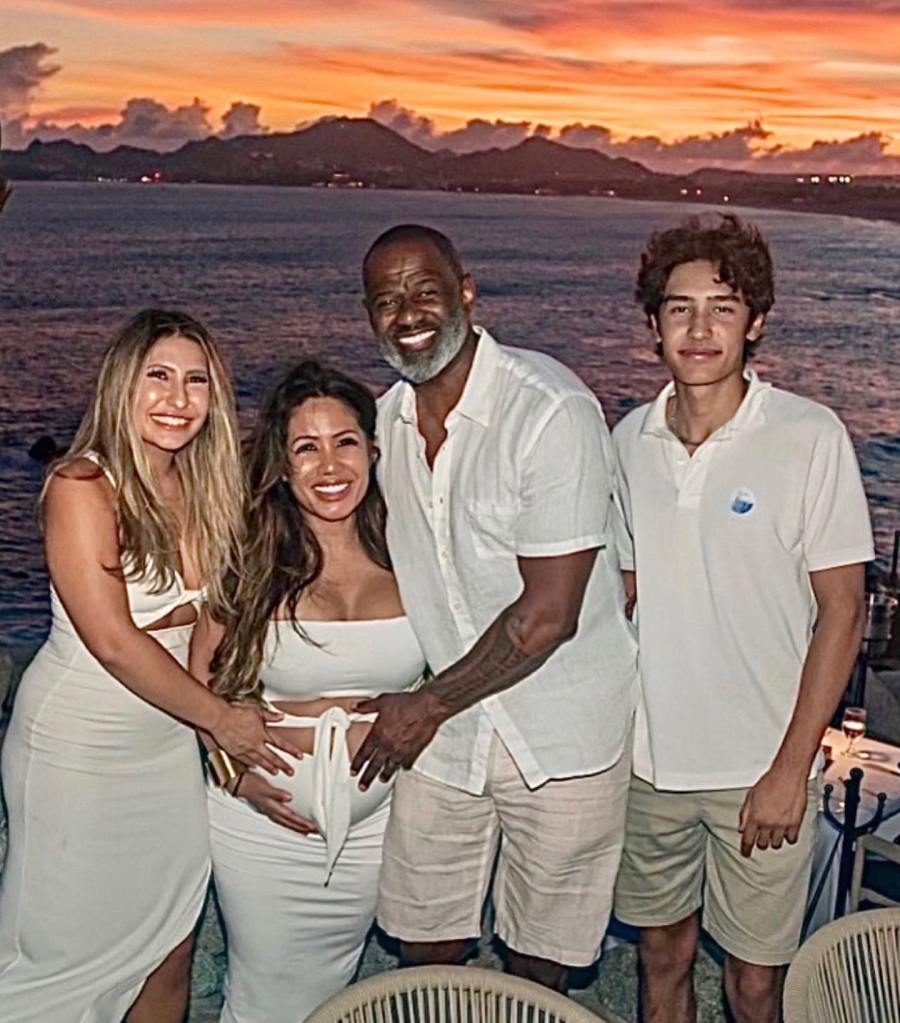 Brian McKnight and Leilani with a woman and a young man, standing against a sunset over the water.