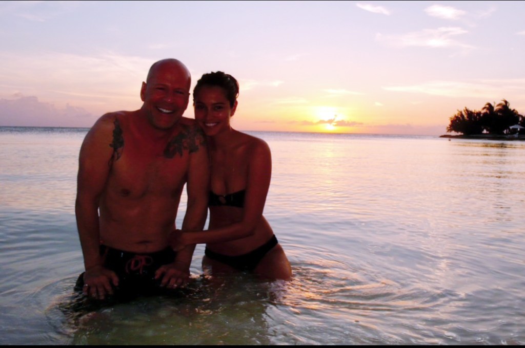 Emma Heming Willis and Bruce Willis in the ocean at sunset.