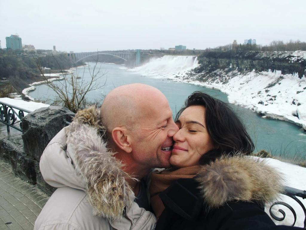 Emma Heming Willis with husband Bruce Willis, embracing in front of Niagara Falls.