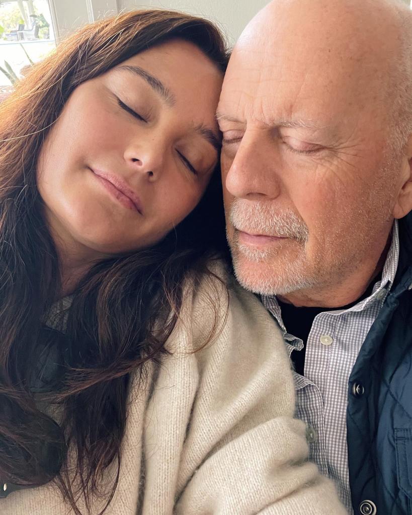 Emma Heming Willis and Bruce Willis with their eyes closed, cheek to cheek.
