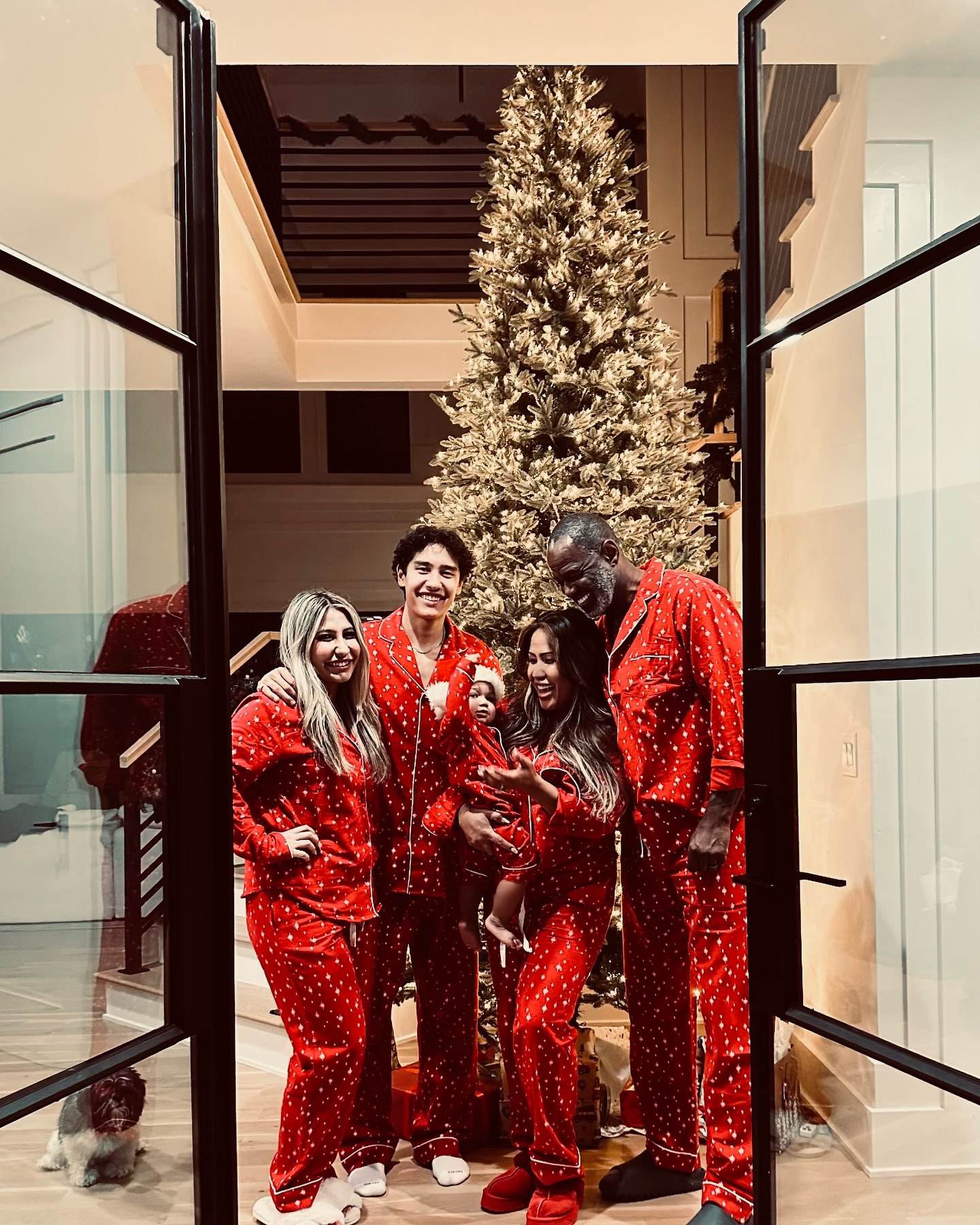 Brian McKnight and Leilani with their family in matching red pajamas in front of a Christmas tree.