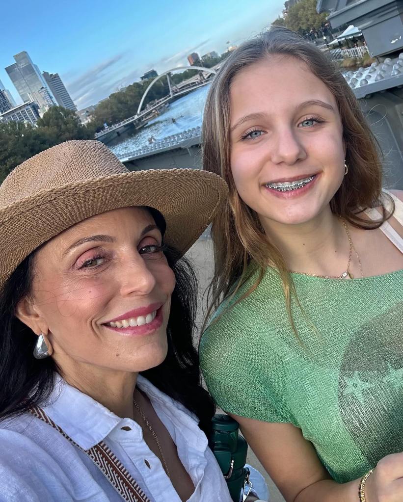 Bethenny Frankel and daughter Bryn posing for a selfie with a city skyline and water in the background.