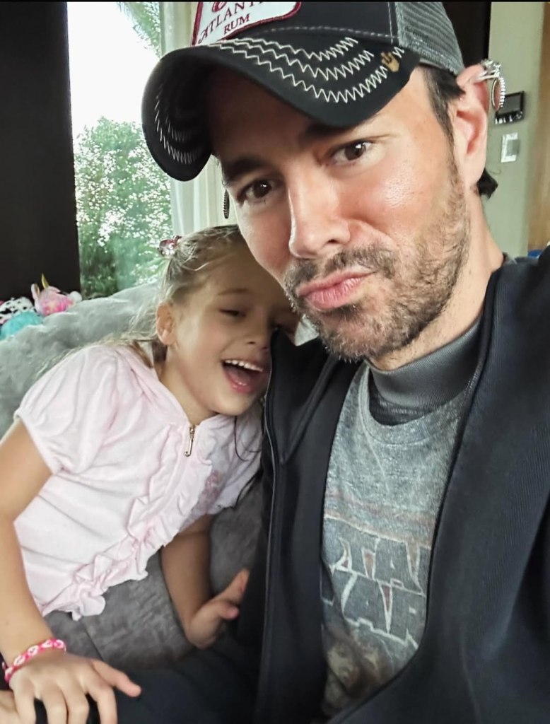 Enrique Iglesias and a young girl pose for a photo.