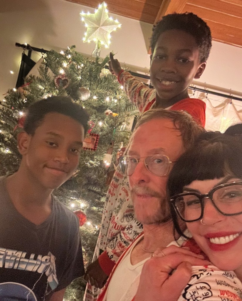 Jillian Lauren, Scott Shriner, and their two sons in front of a Christmas tree.