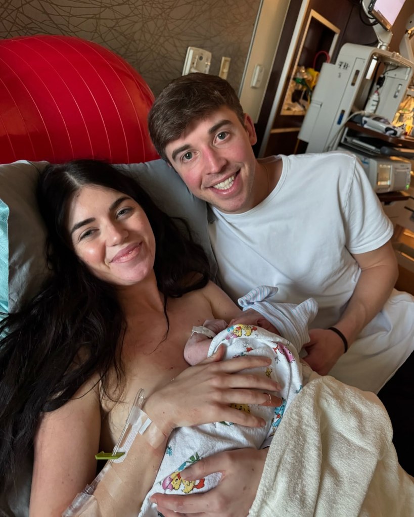 New parents Madison Prewett and Grant Troutt smiling and holding their newborn baby in a hospital room.
