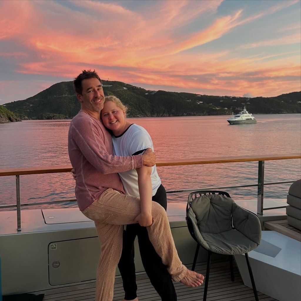 Amy Schumer and her husband embrace on a boat at sunset.