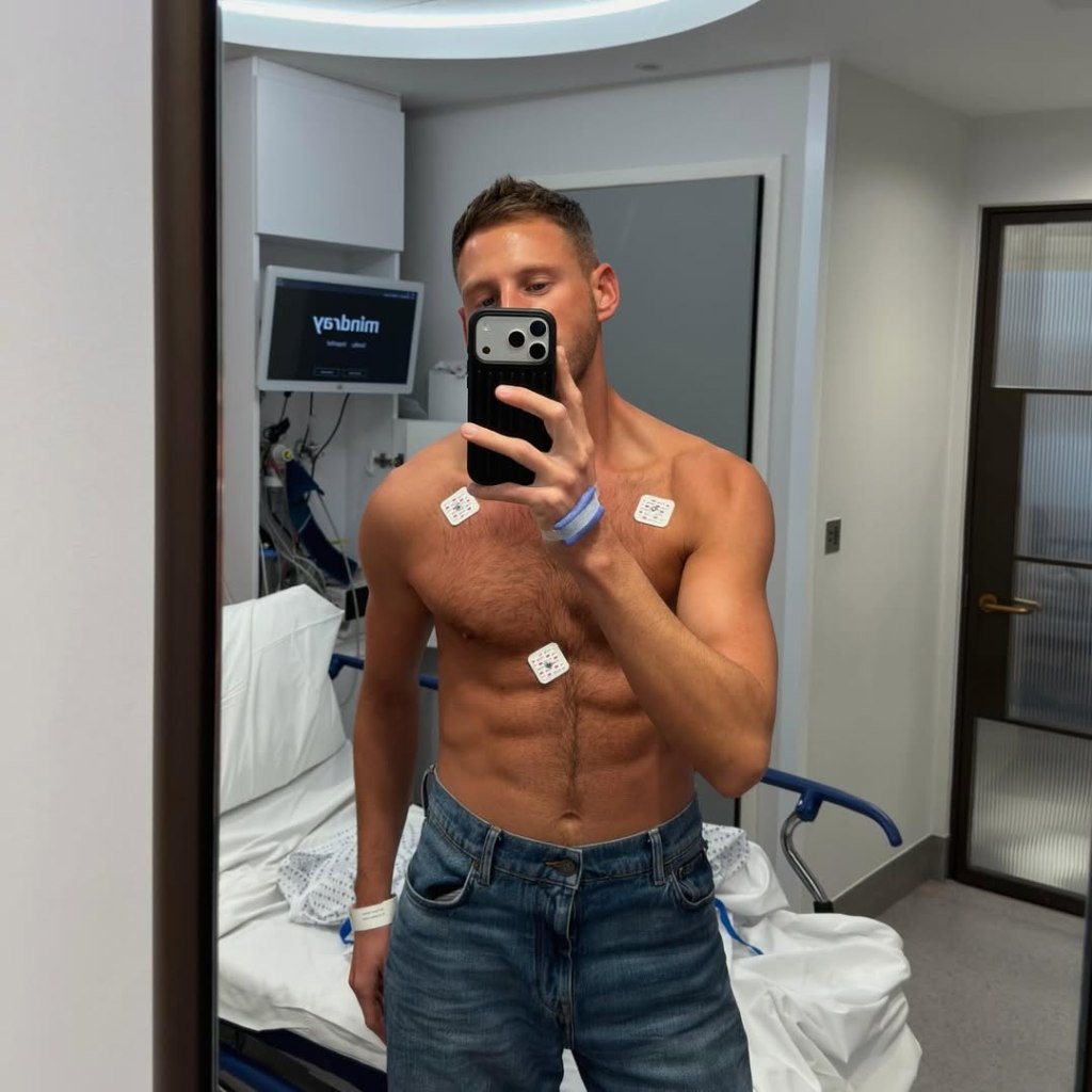Fraser Olender shirtless with medical electrodes on his chest, taking a mirror selfie in a hospital room.