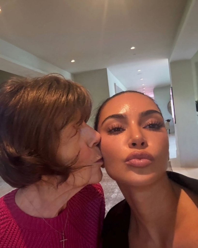 Kim Kardashian posing for a selfie while being kissed on the cheek by an older woman.