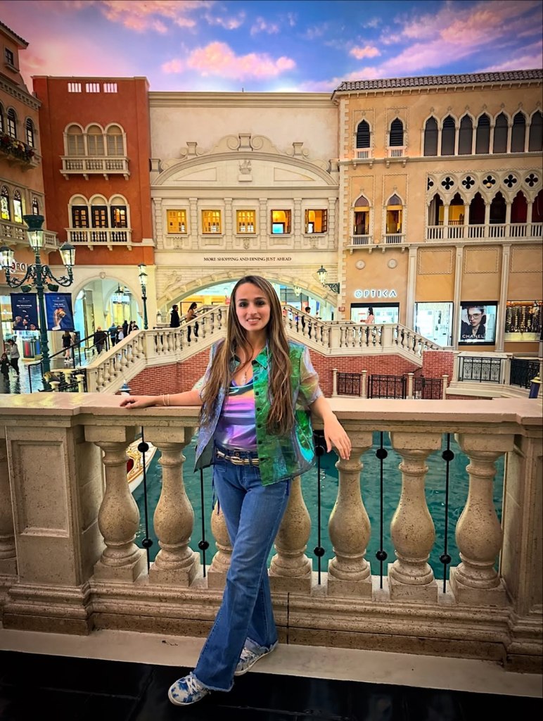 Jazz Jennings posing in front of a Venetian-themed indoor canal and buildings.