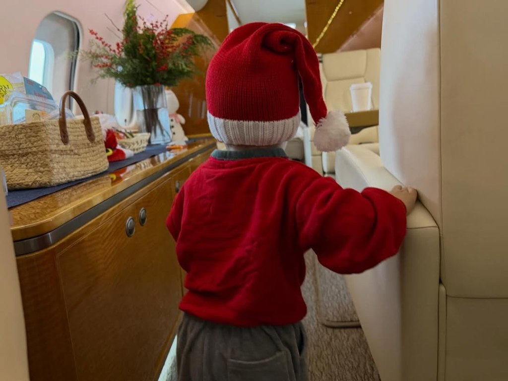 Son Jack in a Santa hat and red top aboard a private jet.
