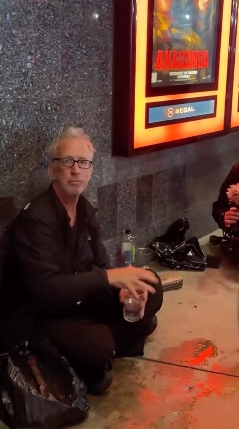 Andy Dick sitting on the ground in downtown Los Angeles.