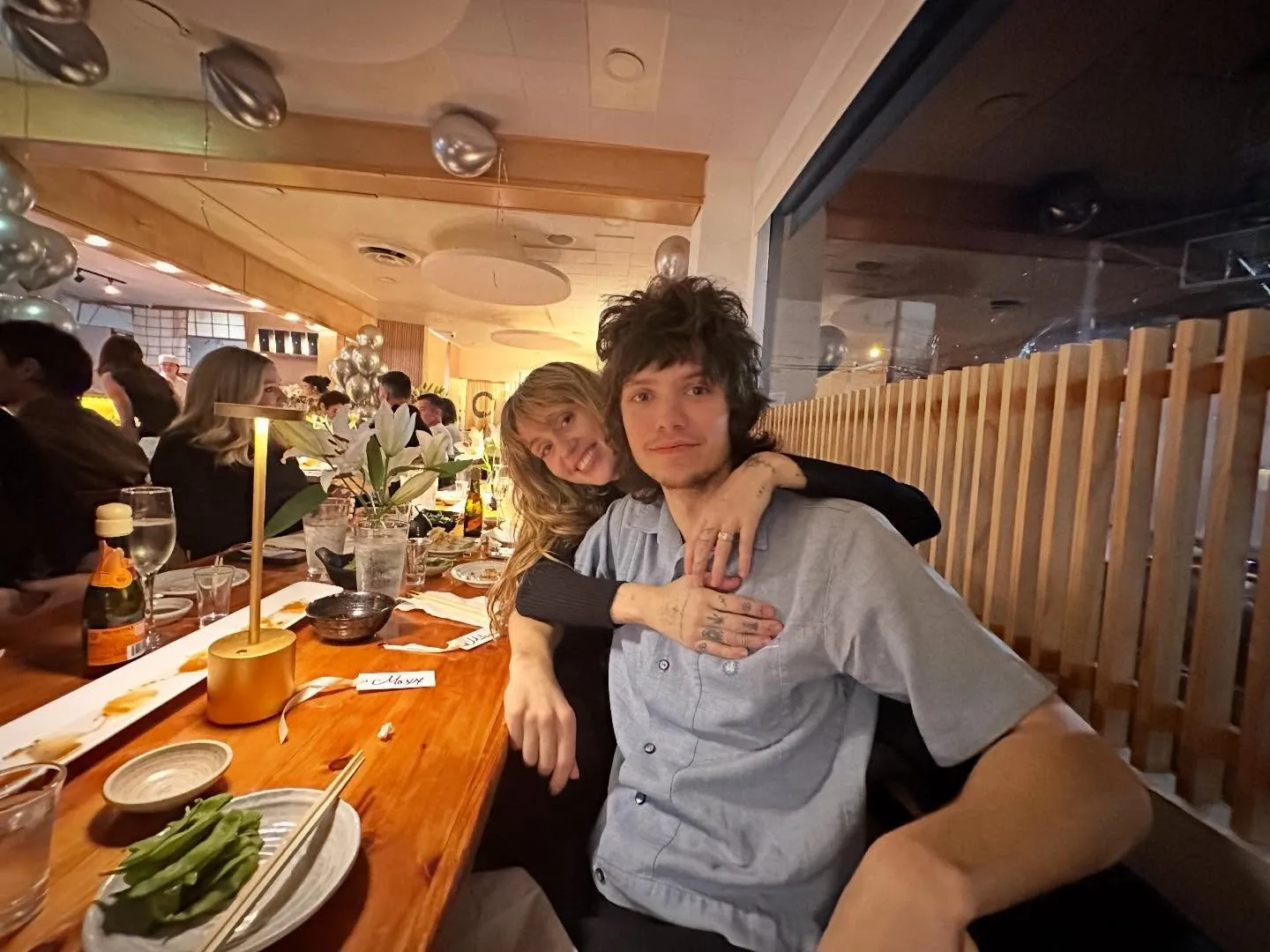 Miley Cyrus and Maxx Morando embracing at a dinner table.