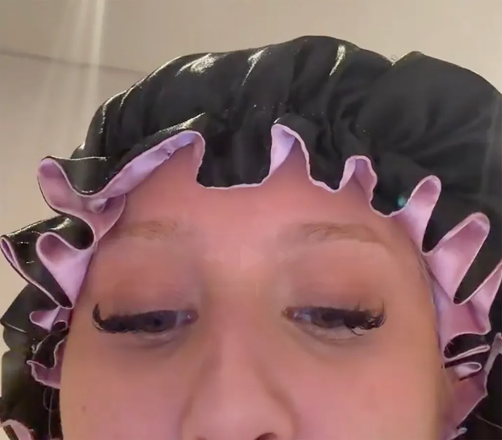 A person wearing a black and pink shower cap with long eyelashes.