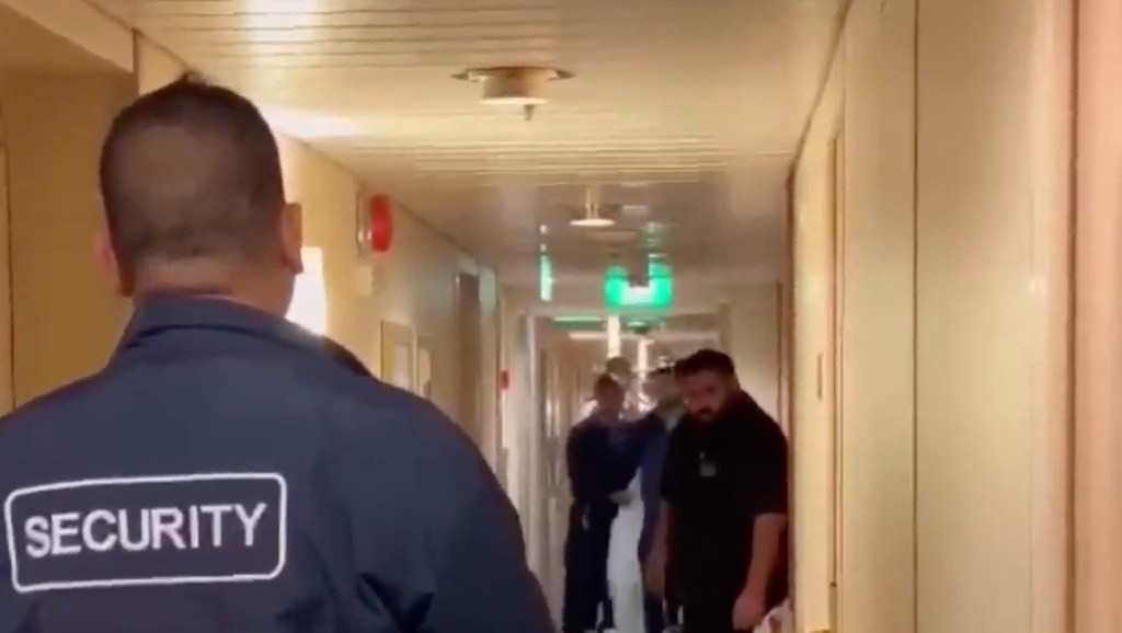 Security personnel escorting a passenger on a cruise ship.