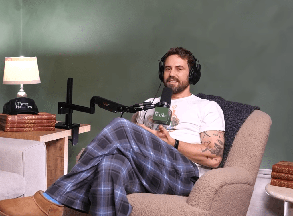 Nick Viall sitting in a chair with headphones and microphone.