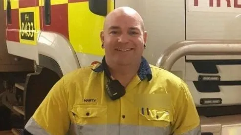 Martin Thomas Glynn smiling, wearing a yellow work shirt with 