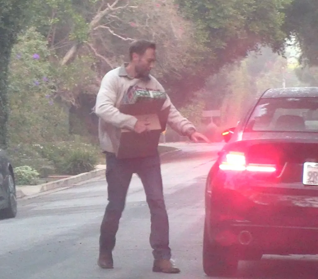 John Miller carrying Christmas gifts near a car with its brake lights on.