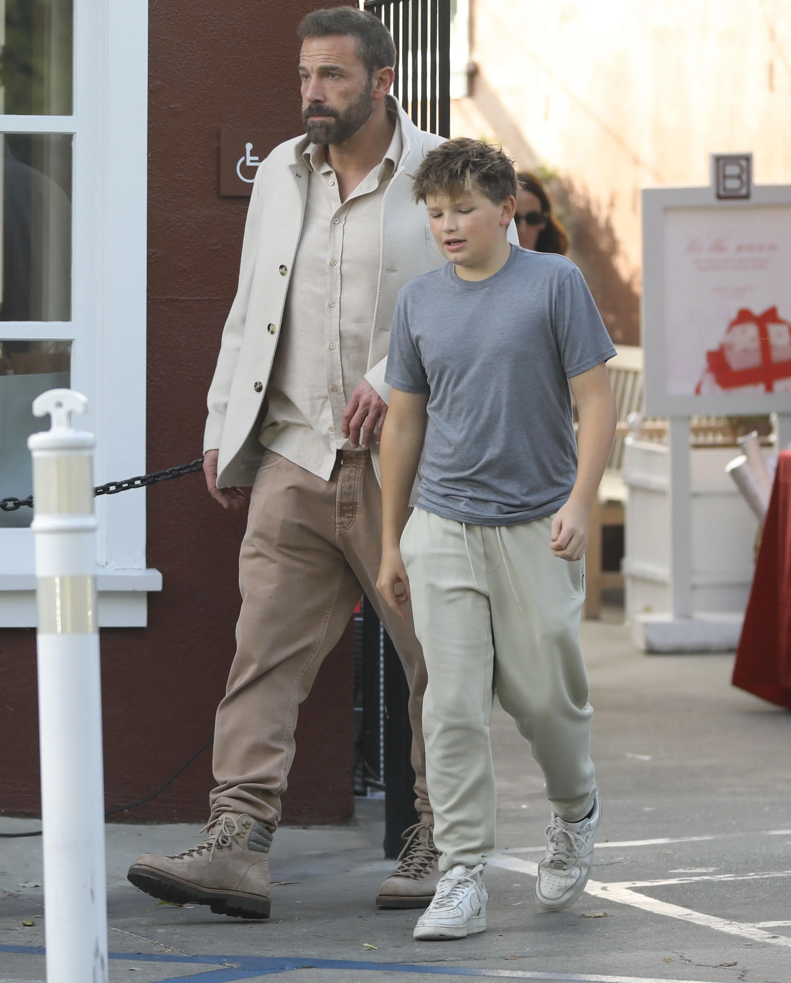 Ben Affleck and his son, Samuel, walk past a brown building.