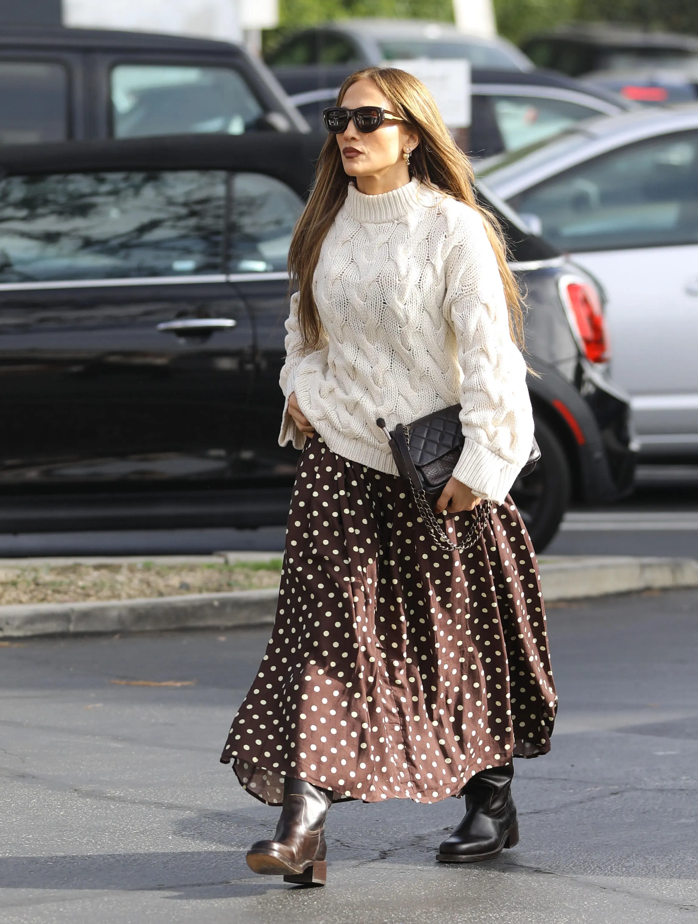 Jennifer Lopez in a white cable knit sweater and a brown polka dot skirt.
