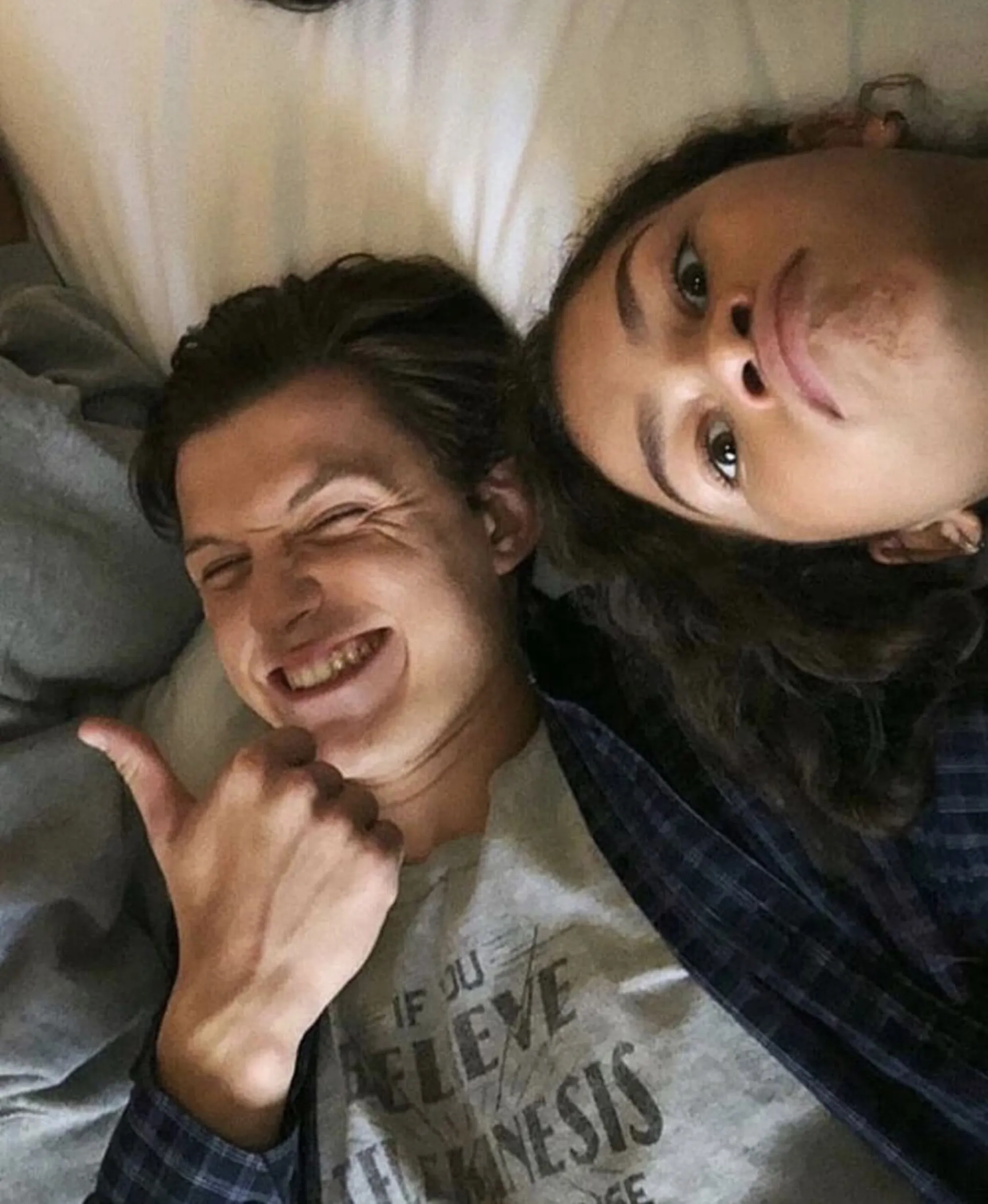 Zendaya and Tom Holland looking up at the camera while lying down.