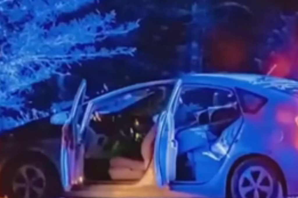 A car with its doors open at night, with blue and red lights suggesting an emergency.