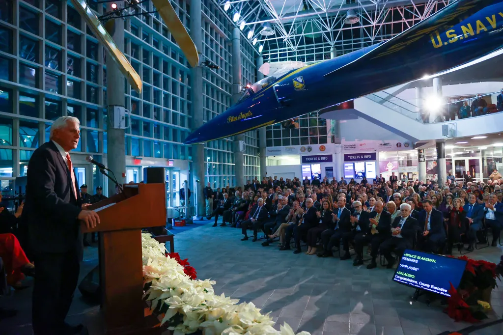 Bruce Blakeman speaking at a podium while being sworn in for his second term as Nassau County Executive at the Cradle of Aviation Museum.