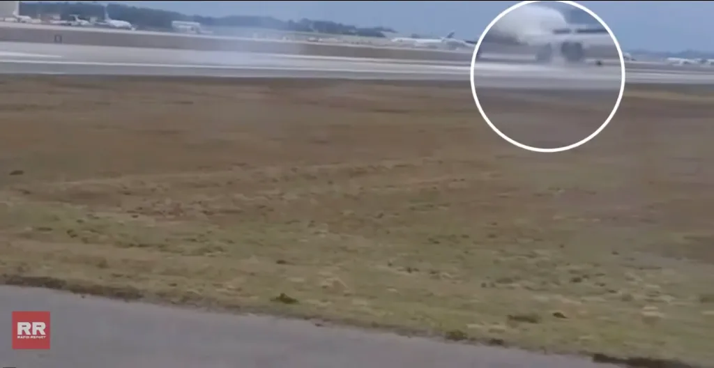 An airplane landing on a wet runway, kicking up spray from its wheels.