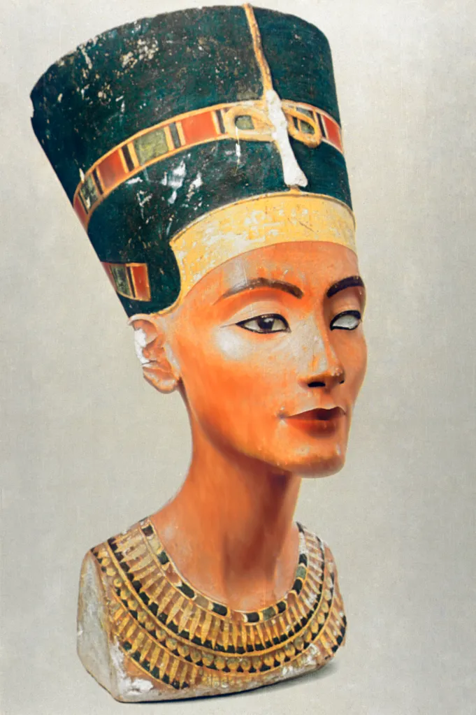 Bust of Queen Nefertiti with a tall, blue headdress and a detailed collar.