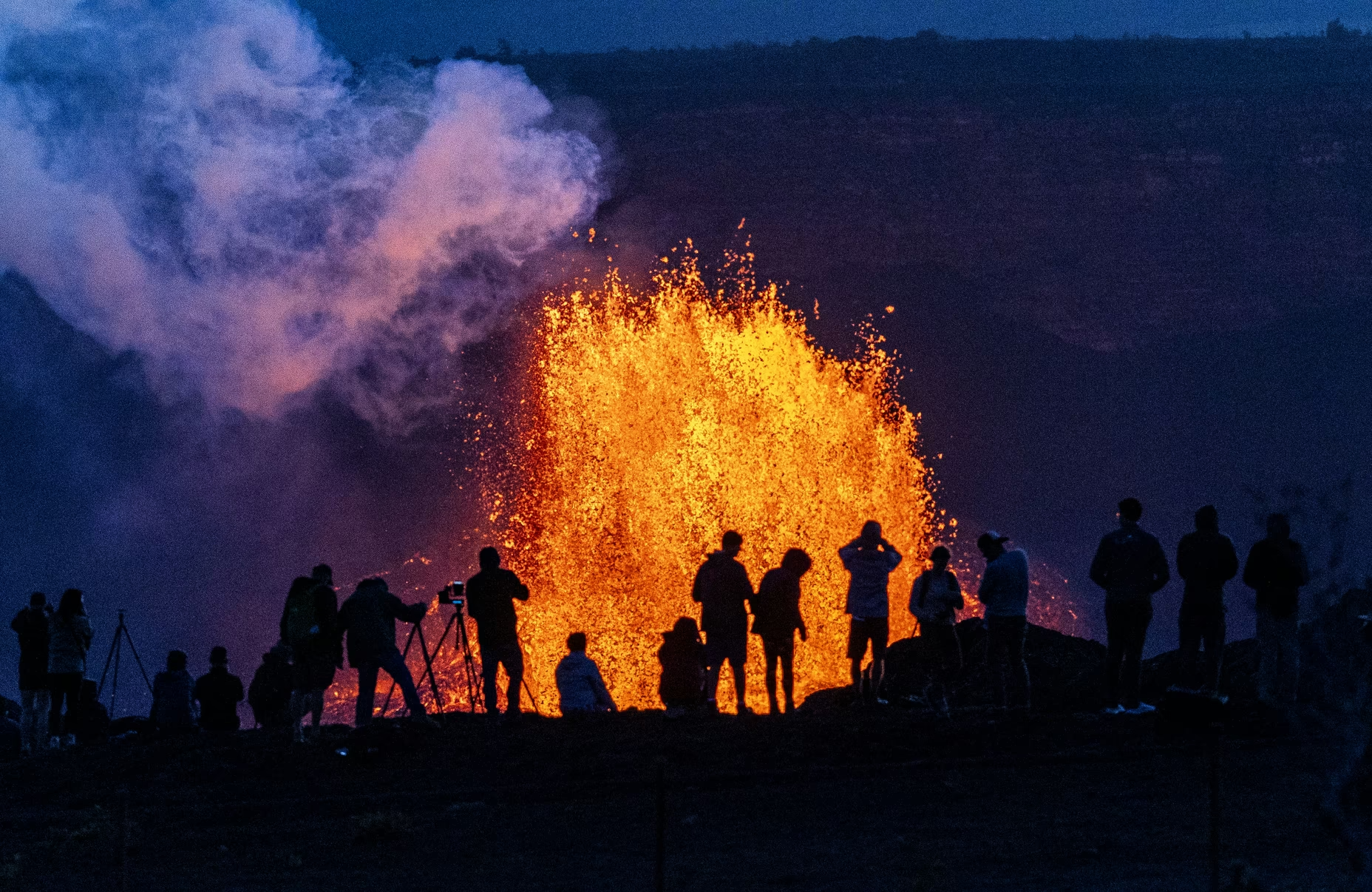 People watch as Hawaii’s Kīlauea volcano erupts on May 11, 2025.