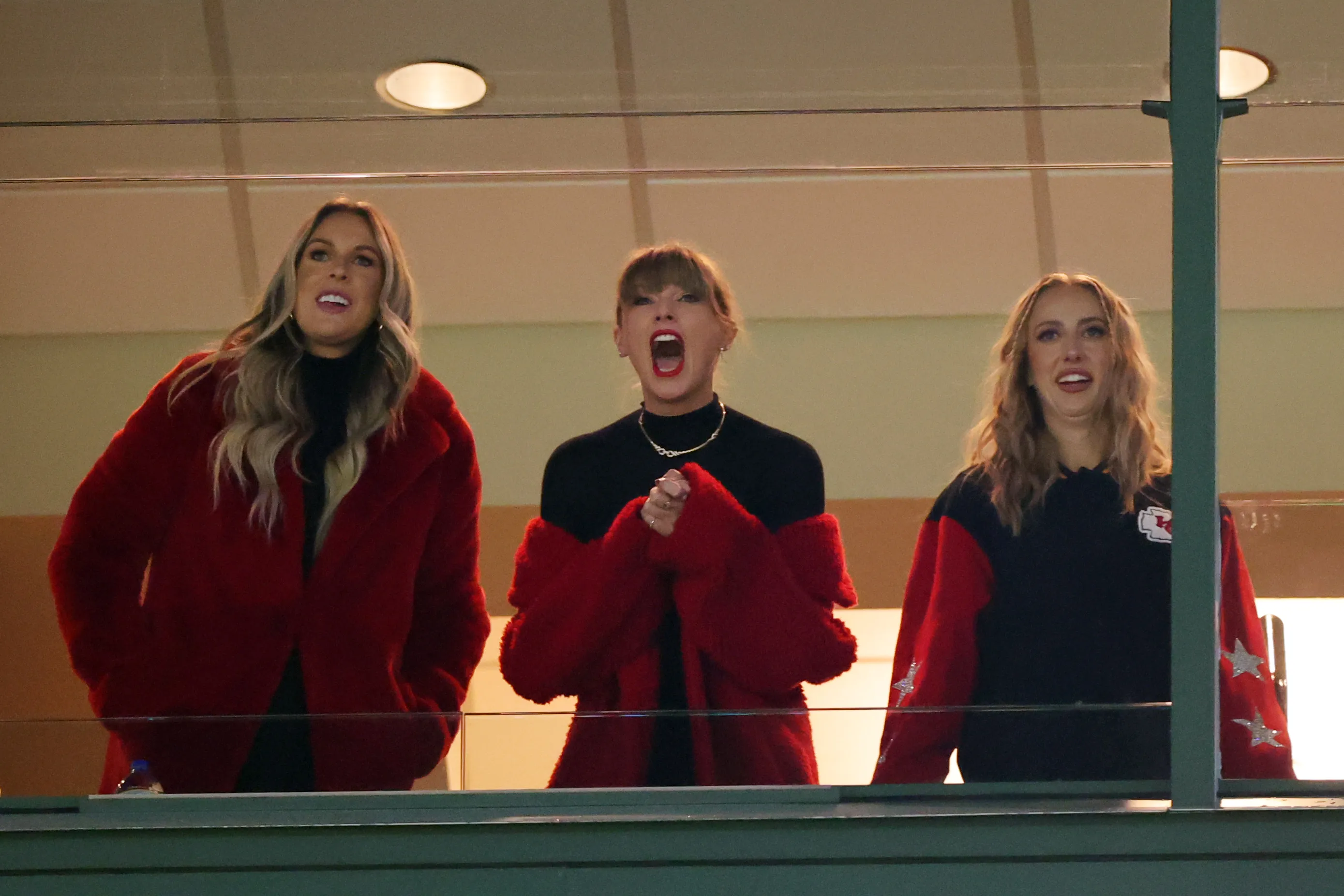 Lyndsay Bell, Taylor Swift, and Brittany Mahomes reacting in a suite at Lambeau Field.