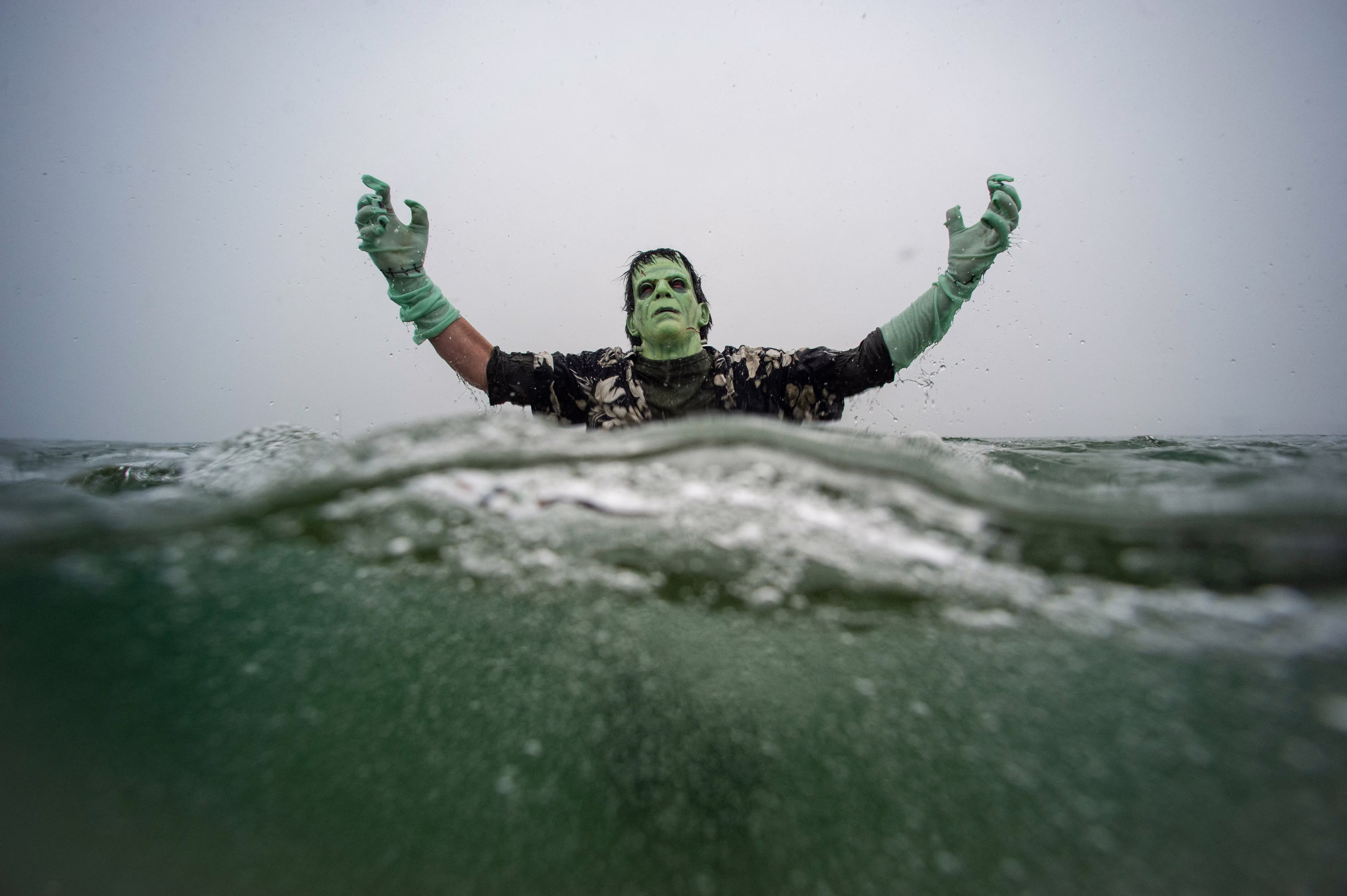 A reveler dressed as Frankenstein's monster plunges into the ocean during a polar bear plunge event.